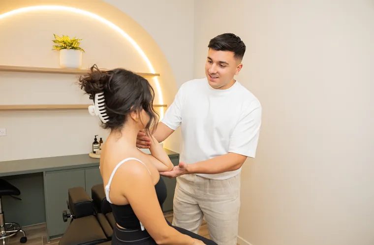 A BellPoint practitioner assessing a patient's shoulder and elbow mobility in a treatment room