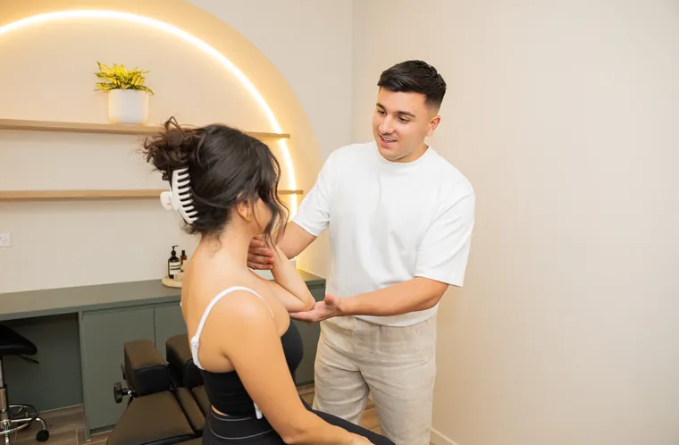 A BellPoint practitioner assessing a patient's shoulder and elbow mobility in a treatment room